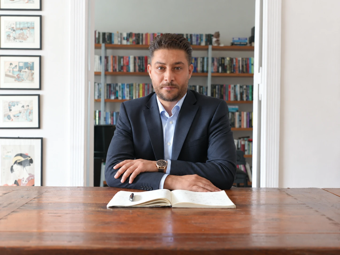 Jamal Hajjo sitzt am Tisch mit einem geöffneten Notizbuch